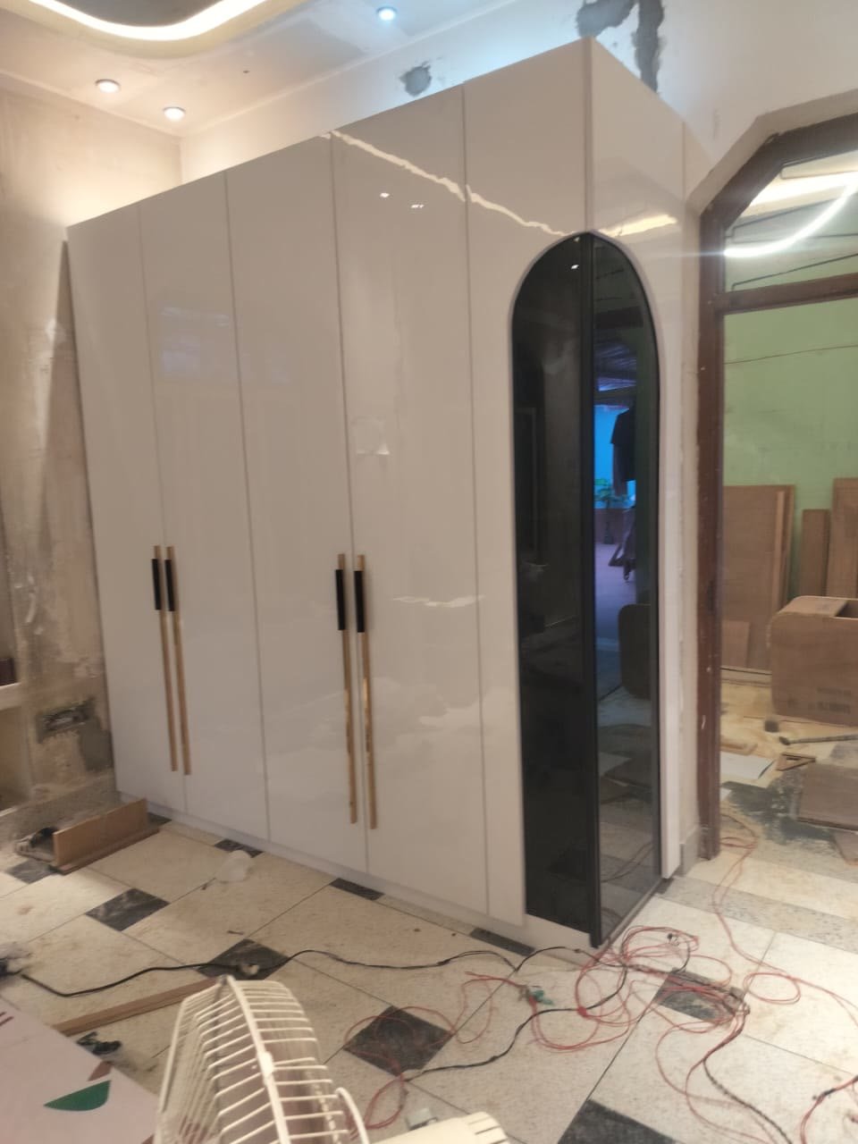 Tall wardrobe with arched black mirror door and gold handles