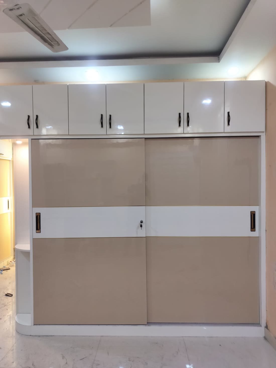 Beige and white sliding wardrobe with overhead storage cabinets