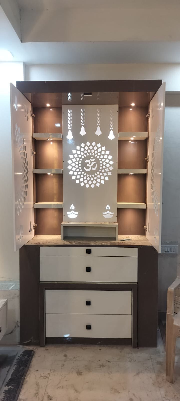 Pooja mandir unit interior with illuminated Om motif and shelving